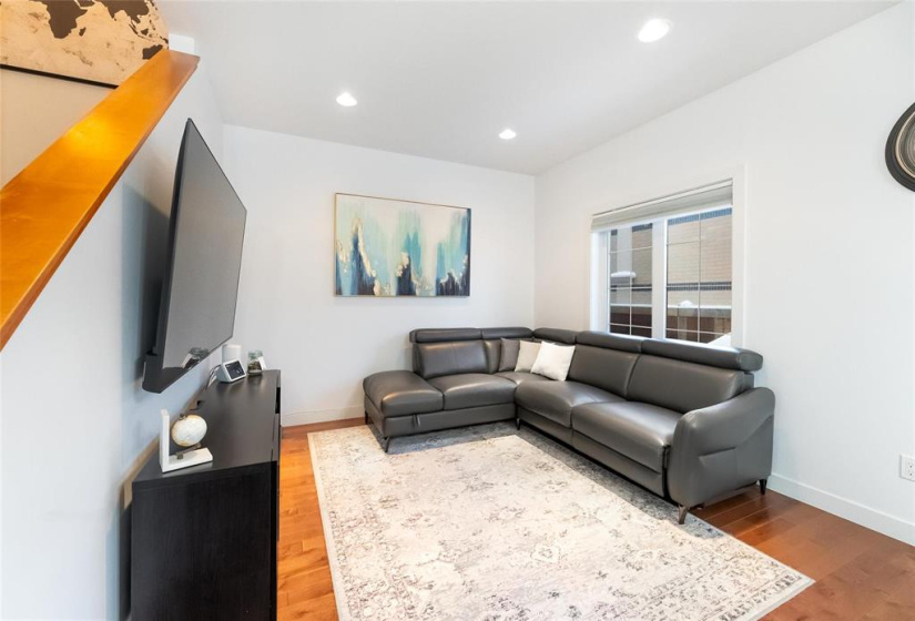 Living room with hardwood floors, pot lighting and neutral decor